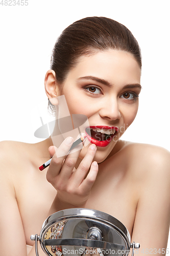 Image of girl applying red lipstick isolated on white