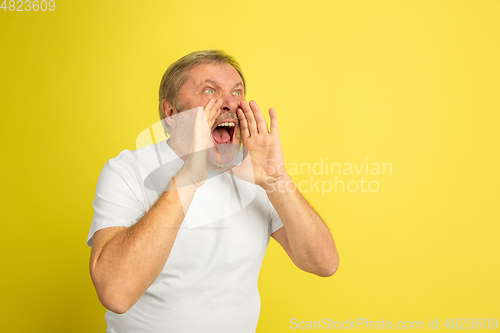 Image of Caucasian senior man\'s portrait isolated on yellow studio background