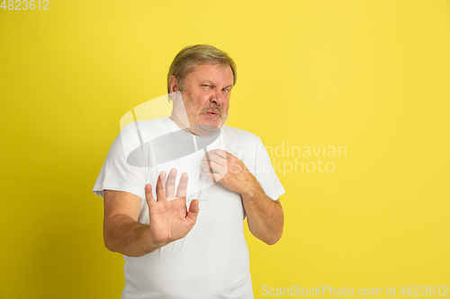 Image of Caucasian senior man\'s portrait isolated on yellow studio background