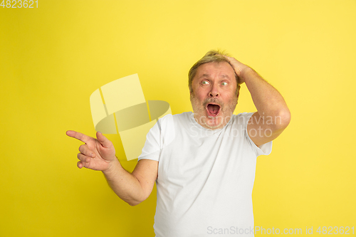 Image of Caucasian senior man\'s portrait isolated on yellow studio background