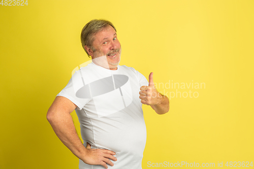 Image of Caucasian senior man\'s portrait isolated on yellow studio background