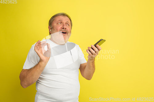 Image of Caucasian senior man\'s portrait isolated on yellow studio background