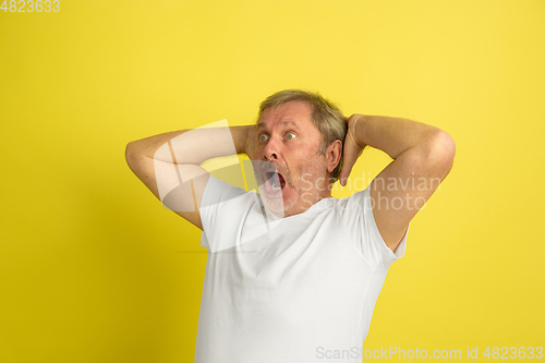 Image of Caucasian senior man\'s portrait isolated on yellow studio background