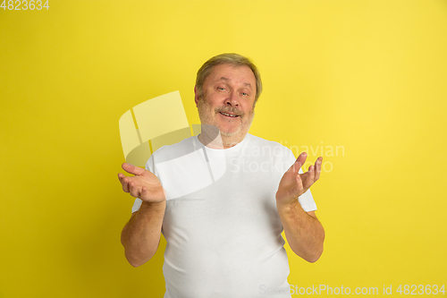 Image of Caucasian senior man\'s portrait isolated on yellow studio background