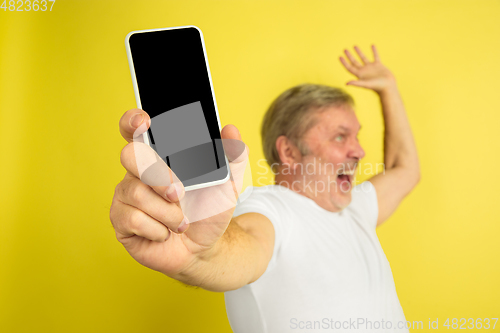 Image of Caucasian senior man\'s portrait isolated on yellow studio background