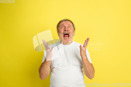 Image of Caucasian senior man\'s portrait isolated on yellow studio background