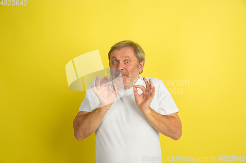 Image of Caucasian senior man\'s portrait isolated on yellow studio background