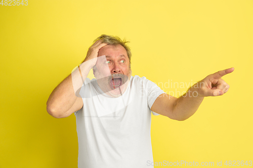 Image of Caucasian senior man\'s portrait isolated on yellow studio background