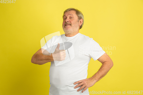 Image of Caucasian senior man\'s portrait isolated on yellow studio background