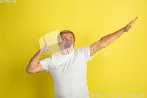 Image of Caucasian senior man\'s portrait isolated on yellow studio background