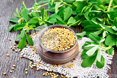 Image of Fenugreek in bowl with leaves on dark wooden board