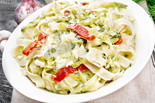 Image of Fettuccine with zucchini and hot peppers in plate on dark wooden