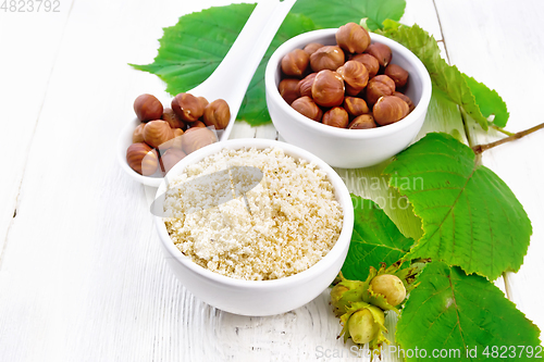 Image of Flour and hazelnuts in bowls on white wooden board