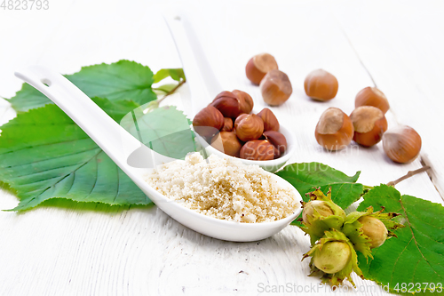 Image of Flour and hazelnuts in spoons on light board