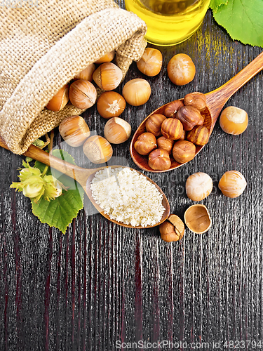 Image of Flour and hazelnuts in two spoons on dark board top