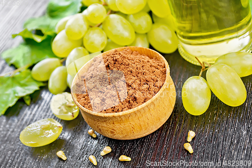 Image of Flour grape seed in bowl on dark wooden board