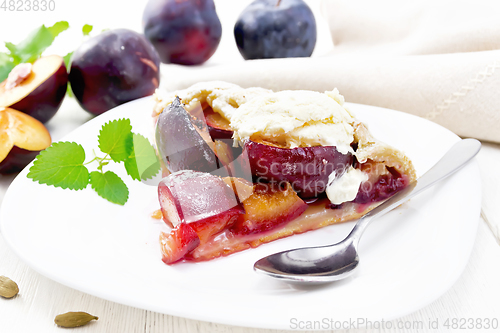 Image of Galeta with plums in plate on white wooden board