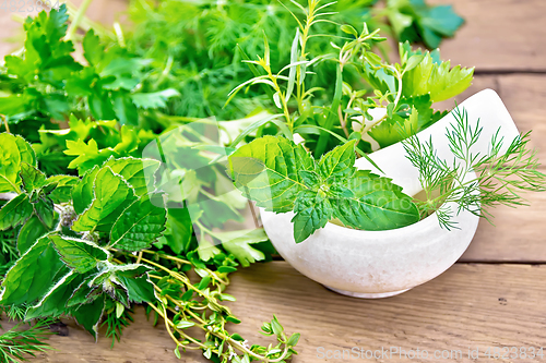 Image of Herbs spicy in stone mortar on board