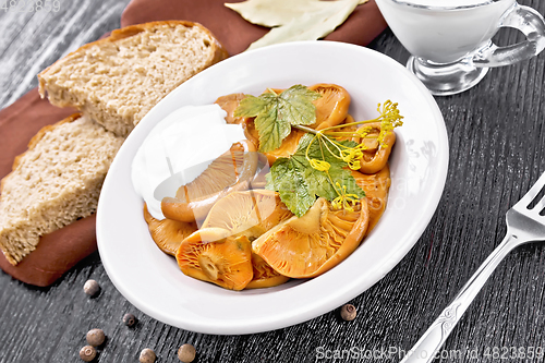 Image of Mushrooms salted with sour cream in plate on wooden board