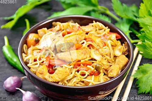 Image of Noodles with cabbage and chicken in bowl on black board