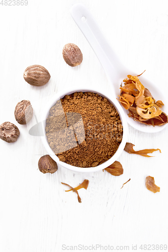 Image of Nutmeg ground in bowl and mace in spoon on board top