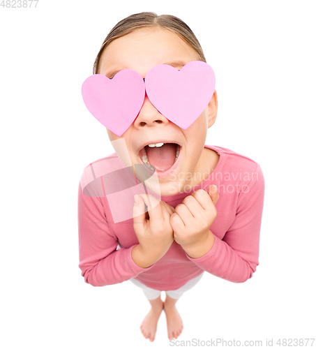 Image of Little girl is holding hearts over her eyes