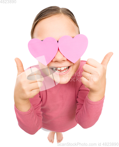 Image of Little girl is holding hearts over her eyes