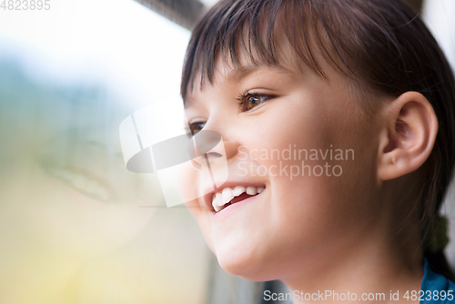 Image of Happy girl is looking through window