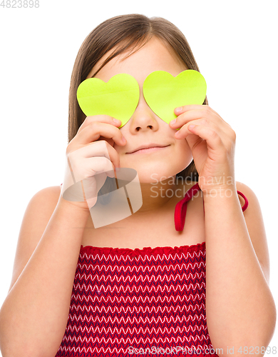 Image of Little girl is holding hearts over her eyes