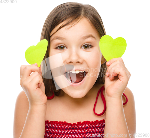 Image of Little girl is holding hearts near her eyes