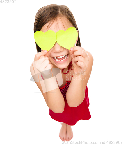 Image of Little girl is holding hearts over her eyes