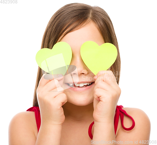 Image of Little girl is holding hearts over her eyes