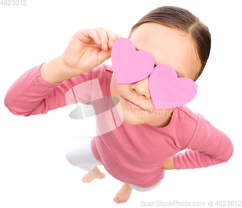 Image of Little girl is holding hearts over her eyes