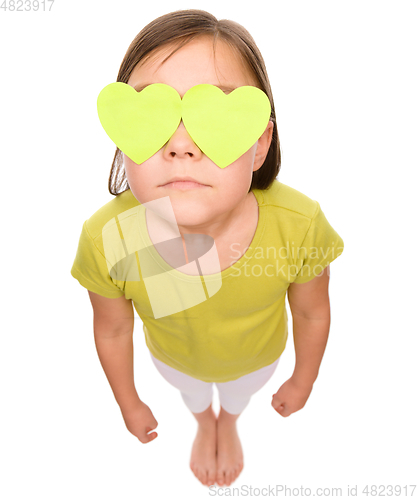 Image of Little girl is holding hearts over her eyes