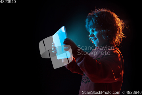 Image of Caucasian boy\'s portrait isolated on dark studio background in neon light