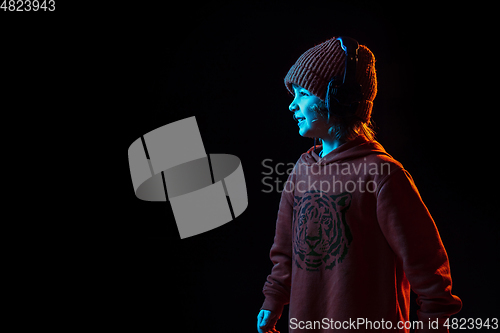 Image of Caucasian boy\'s portrait isolated on dark studio background in neon light