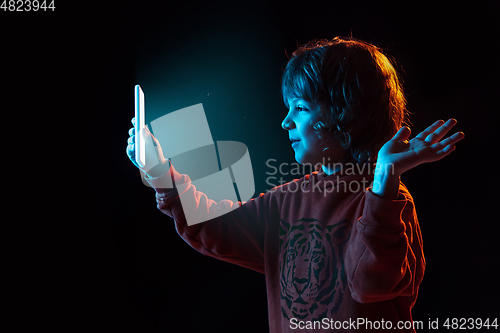 Image of Caucasian boy\'s portrait isolated on dark studio background in neon light