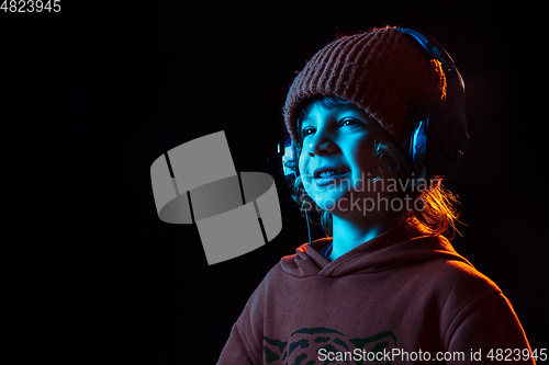 Image of Caucasian boy\'s portrait isolated on dark studio background in neon light