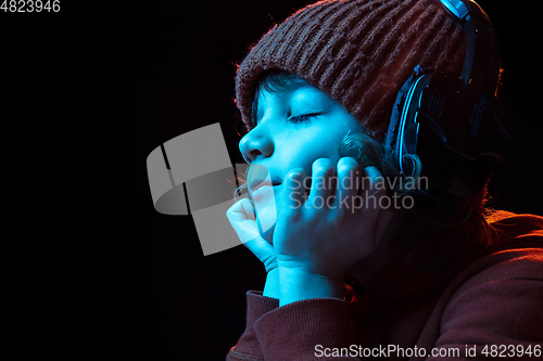 Image of Caucasian boy\'s portrait isolated on dark studio background in neon light