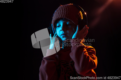 Image of Caucasian boy\'s portrait isolated on dark studio background in neon light