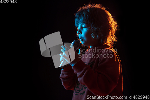 Image of Caucasian boy\'s portrait isolated on dark studio background in neon light