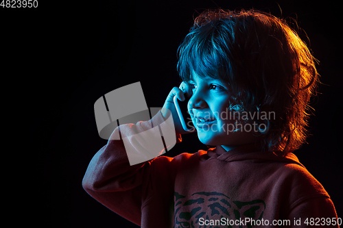 Image of Caucasian boy\'s portrait isolated on dark studio background in neon light