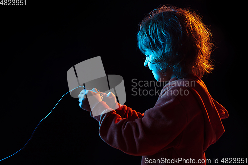 Image of Caucasian boy\'s portrait isolated on dark studio background in neon light