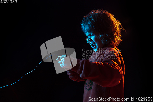 Image of Caucasian boy\'s portrait isolated on dark studio background in neon light