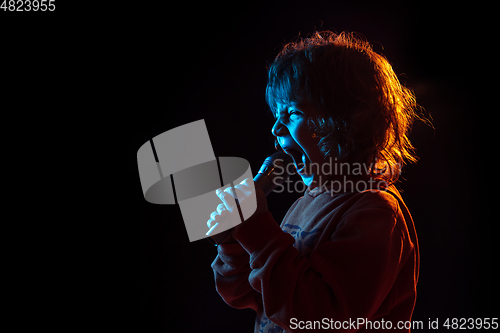 Image of Caucasian boy\'s portrait isolated on dark studio background in neon light