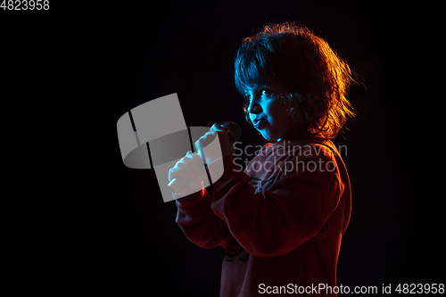 Image of Caucasian boy\'s portrait isolated on dark studio background in neon light