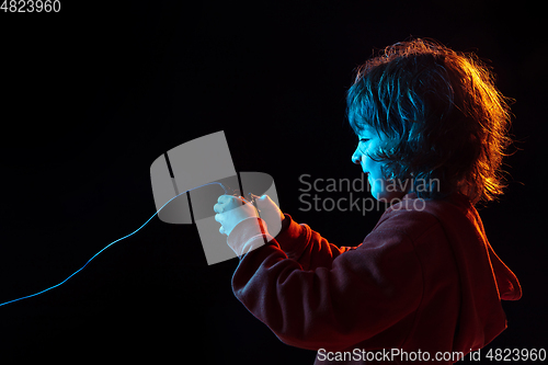 Image of Caucasian boy\'s portrait isolated on dark studio background in neon light