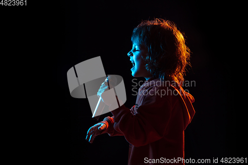 Image of Caucasian boy\'s portrait isolated on dark studio background in neon light