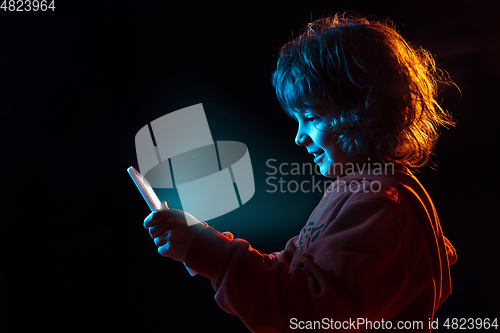 Image of Caucasian boy\'s portrait isolated on dark studio background in neon light