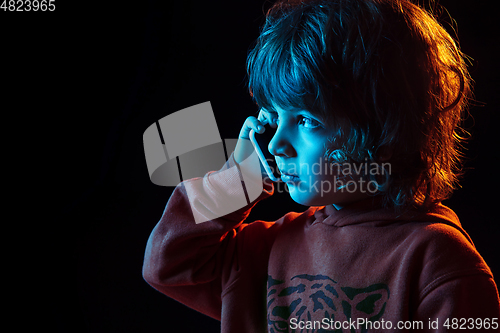 Image of Caucasian boy\'s portrait isolated on dark studio background in neon light